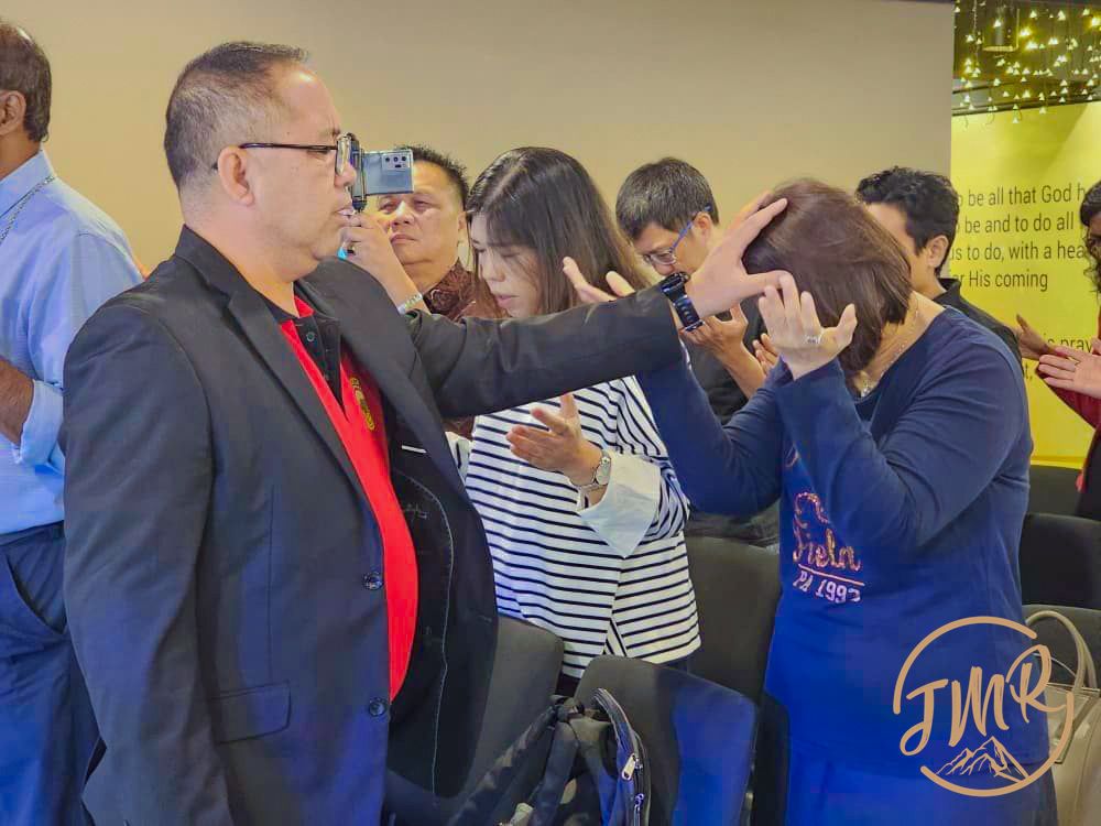 Rev Romed lay hand on a lady to pray for her