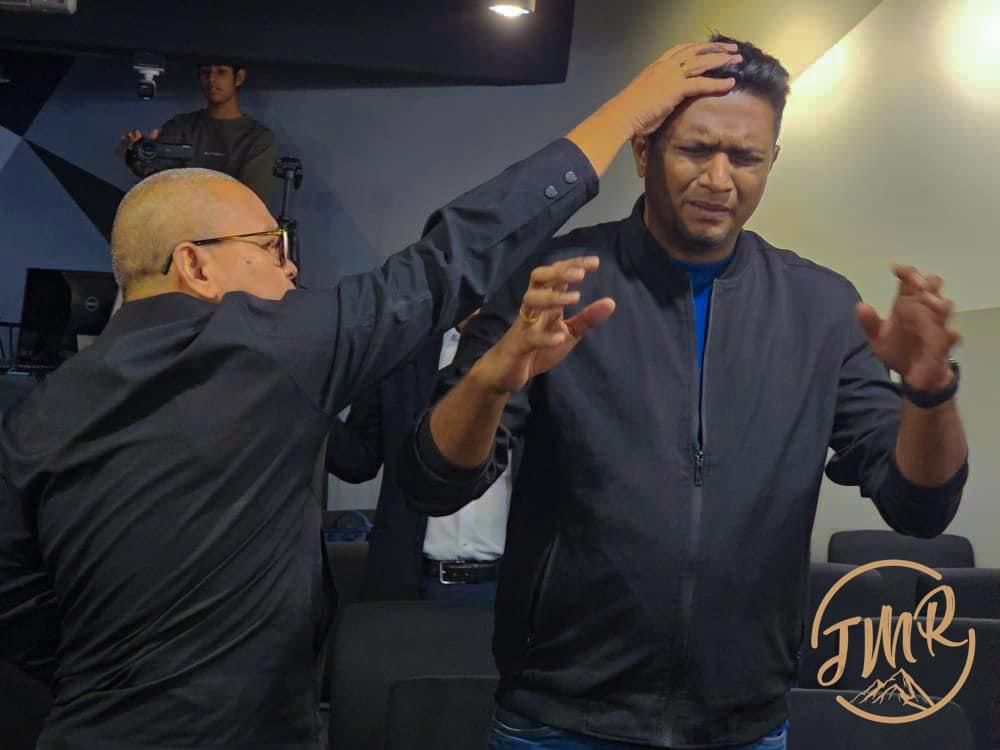Rev Danny from Philippines lay hand to pray for a person.